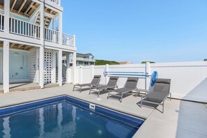 Relax by the pool surrounded by lounge chairs and a balcony overlooking the surrounding area.