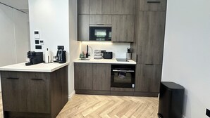 Una cucina compatta con mobili in legno, un forno a microonde, una macchina del caffè e una lavastoviglie.