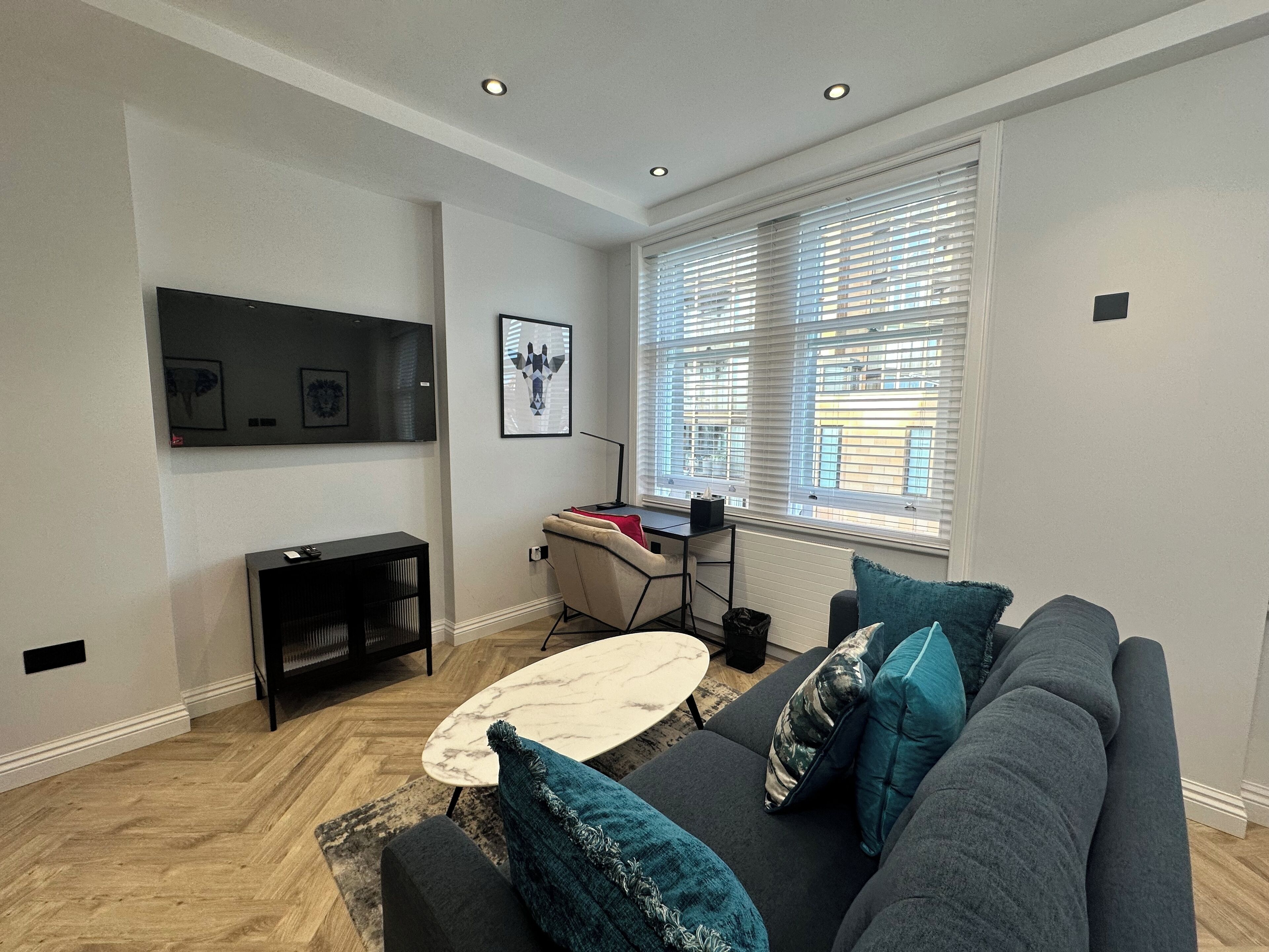 A modern living room with a grey sofa, a coffee table, and a TV mounted on the wall.