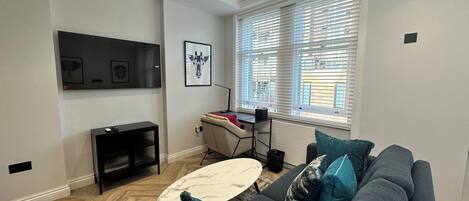 A modern living room with a grey sofa, a coffee table, and a TV mounted on the wall.