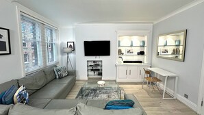 Un salon moderne avec un canapé gris, une table basse et un téléviseur à écran plat.