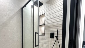 Um banheiro moderno com box de vidro, vaso sanitário e porta-toalhas.