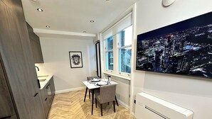Cozinha moderna com área de jantar, vista para a cidade e piso de madeira em padrão herringbone.