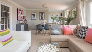 A modern living room with a white sofa, a glass coffee table, and a dining area with chairs and a table. - Stylish 2 Bedroom Flat Apartment with Free Parking in Windsor - Pass the Keys (Windsor)