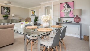 A modern dining area with a glass table, woven placemats, and grey upholstered chairs. - Stylish 2 Bedroom Flat Apartment with Free Parking in Windsor - Pass the Keys (Windsor)