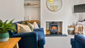 Una sala de estar moderna con un sofá azul, una chimenea, un televisor y un espejo redondo en la pared.