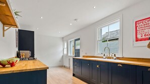 Una cocina moderna con armarios oscuros, una encimera de madera y un ventanal que proporciona luz natural.