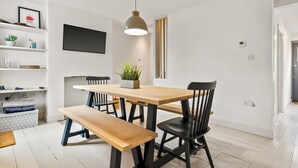 Un comedor moderno con una mesa de madera, sillas negras, un banco y una lámpara colgante.