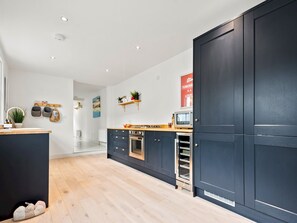 A modern kitchen with dark cabinetry, a wooden countertop, and a built-in oven.