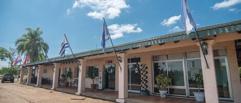 A building with multiple flags, a covered entrance, and potted plants.