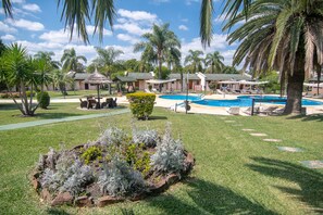 A resort with a swimming pool, palm trees, and lounge areas. - Arapey Oasis Termal (Termas del Arapey)