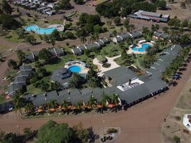 Vista aérea de un resort con varias piscinas, un patio central y filas de villas con techos verdes.