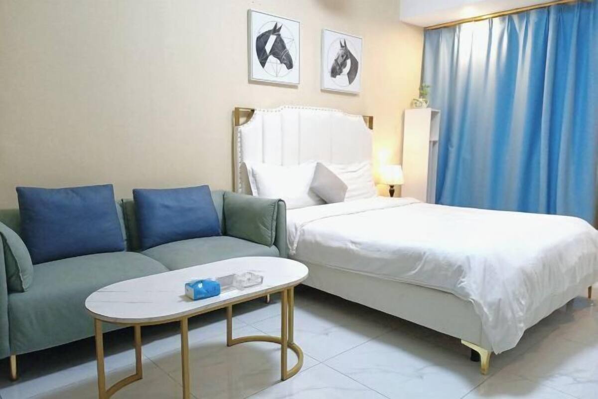 Una habitación de hotel con una cama, un sofá, una mesita y dos obras de arte colgadas en la pared.