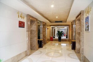 A hotel corridor with marble walls, numbered doors, and a potted plant. - Shenzhen Life Home Apartment (Shenzhen Huaqiangbei Science Museum Subway Station) (Shenzhen)