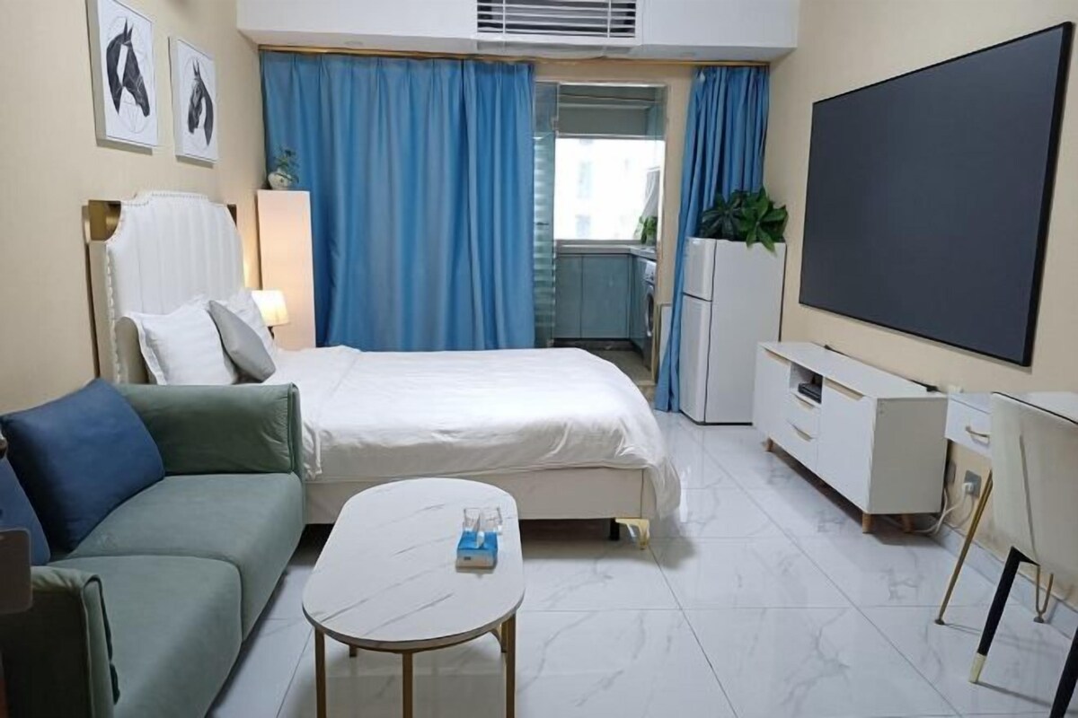 Une chambre d’hôtel équipée d’un lit, d’un canapé, d’une petite table, d’une télévision et d’une kitchenette.