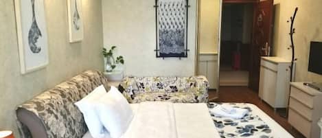 A hotel room with a bed, a sofa, a desk, and a TV.