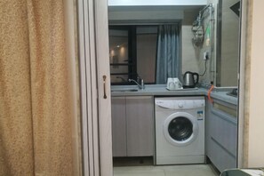 Une cuisine compacte équipée d’un lave-linge, d’une bouilloire et d’un évier.