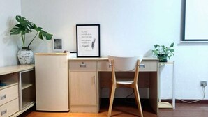 A minimalist office space with a wooden desk, a white chair, a framed inspirational quote on the wall, and a potted plant. - Shenzhen Life Home Apartment (Shenzhen Huaqiangbei Science Museum Subway Station) (Shenzhen)