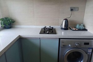 A kitchen area with a gas stove, kettle, and a washing machine. - Shenzhen Life Home Apartment (Shenzhen Huaqiangbei Science Museum Subway Station) (Shenzhen)
