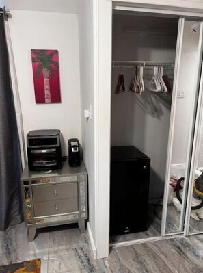 Compact room with a wardrobe, side table, and storage unit.