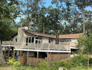 Escape to a serene retreat surrounded by lush greenery and trees, with a spacious deck and a cozy chimney.