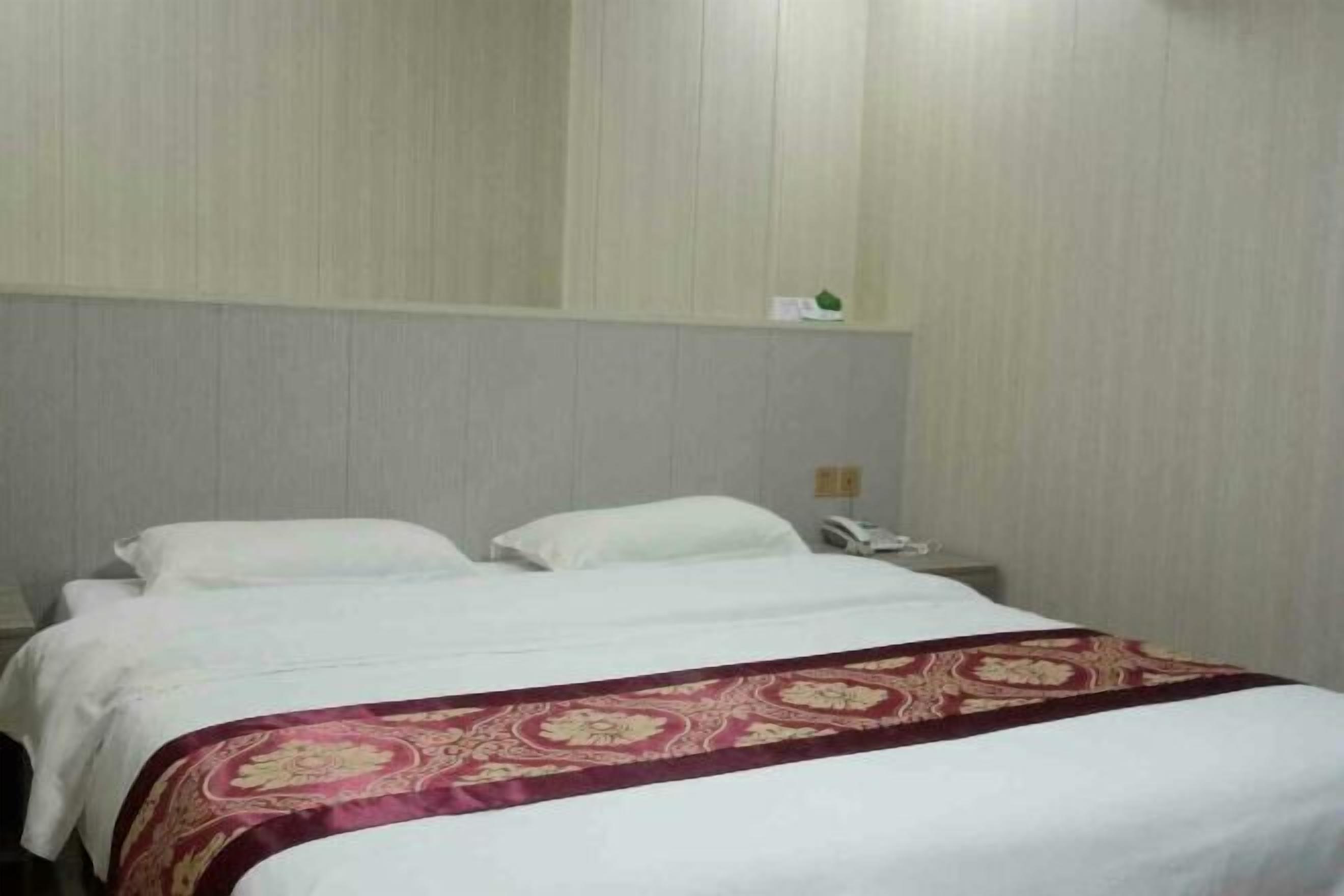 Une chambre d’hôtel avec un grand lit, une table de chevet et un téléphone.