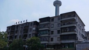 Un edificio de varios pisos con una torre central, balcones y señalización.