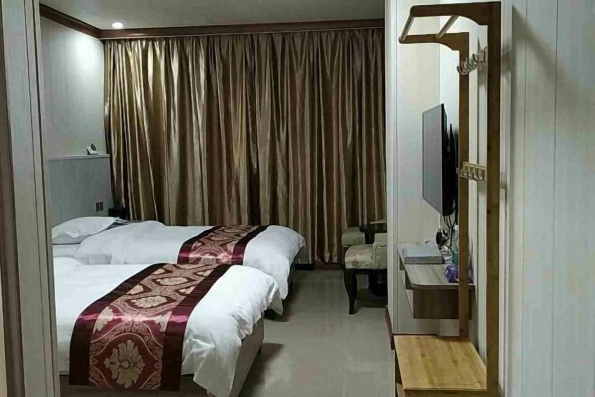 Hotellihuone, jossa on kaksi sänkyä, televisio, pieni työpöytä ja tuoli.
