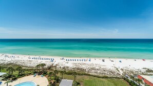 Une plage aux eaux turquoise et limpides, au sable blanc, avec une vue imprenable sur l’océan. Des parasols et des chaises longues sont installés pour permettre aux visiteurs de prendre un bain de soleil.