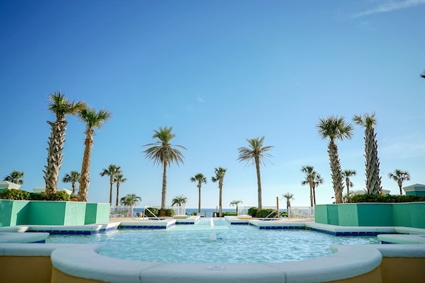 Zona de piscina con palmeras y cielo despejado.