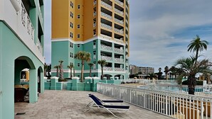 Une cour d’hôtel avec une piscine, des chaises longues et des palmiers.