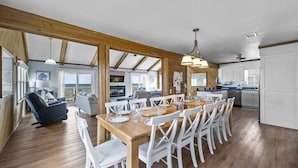 A spacious kitchen with wooden flooring, white cabinets, and a dining area with a wooden table and white chairs.