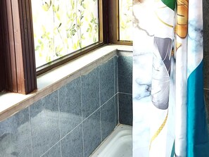 A bathroom with dark blue tiles, a window with a floral pattern, and a curtain with a gold and blue design. - First line of the ocean, 3 bedrooms & Free wifi (Playa de la Américas)