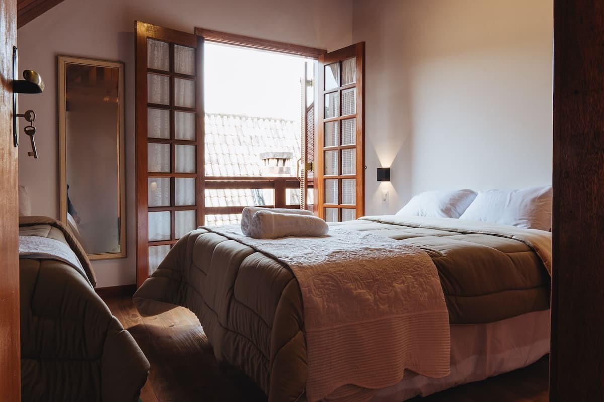A bedroom with a large bed, a wooden door, and a window with a view of a building.