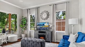 A living room with a fireplace, a blue sofa, a large window, and a television.