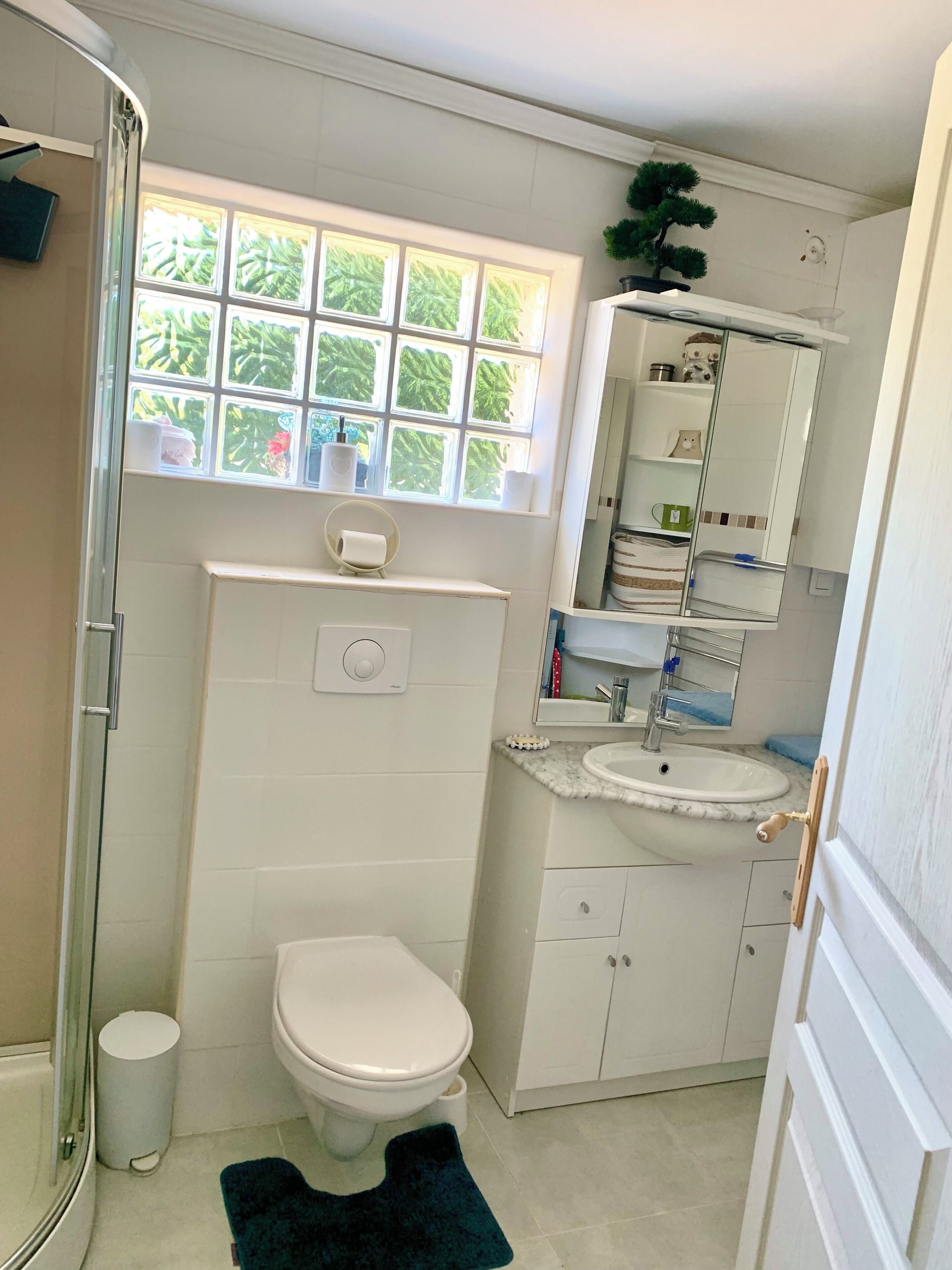 Ein Badezimmer mit Toilette, Waschbecken und einem Fenster mit Blick ins Grüne.