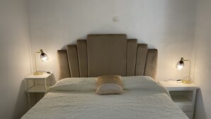 Een bed met hoofdeinde, twee nachtkastjes en twee lampen.