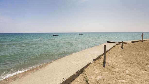 Een strand met een zandrijk strand en kalm water.