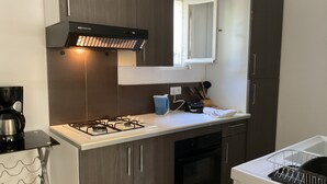 Een moderne keuken met donkerhouten kasten, een gasfornuis, een inbouwoven en een raam boven de spoelbak.