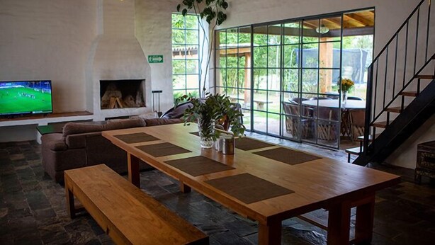 A spacious living area with a large wooden table, a comfortable sofa, and a television. - Cabañas La Serenisima (Tapalpa)
