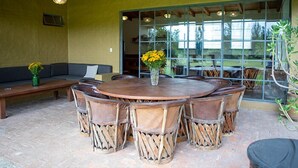 A round wooden table with six chairs, a bench, and a vase with yellow flowers. - Cabañas La Serenisima (Tapalpa)