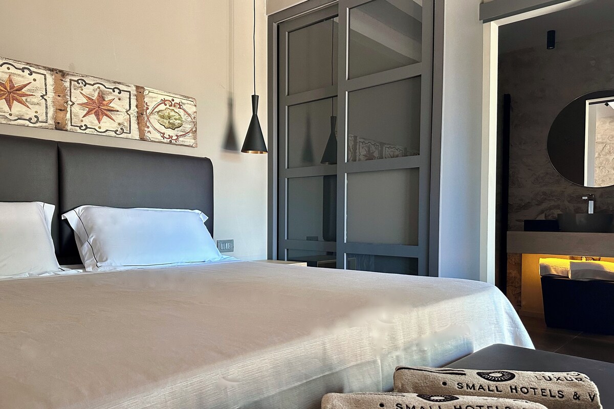 Ein modernes Hotelzimmer mit einem großen Bett, einem Nachttisch, einer Wandlampe und einem Spiegel.