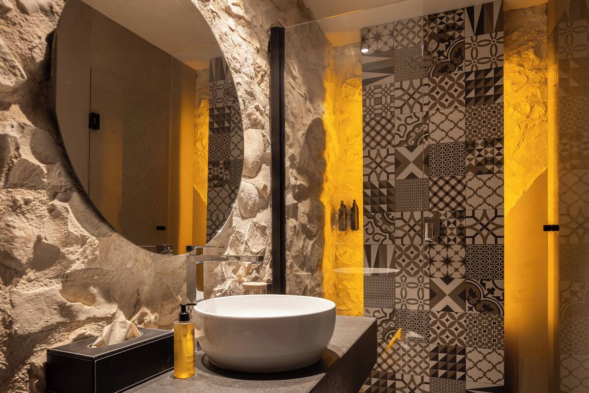 Une salle de bain moderne avec un grand lavabo ovale, un miroir et des carreaux à motifs.
