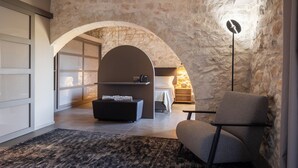 Ein modernes Schlafzimmer im Loft-Stil mit einer Steinwand, einem großen Rundbogen und einem Bett, einem Schreibtisch und einem Stuhl.