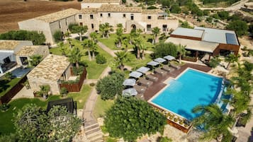 A large building with a courtyard, a swimming pool, and outdoor seating.