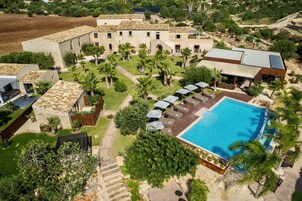 Un grande edificio con un cortile interno, una piscina e posti a sedere all'aperto.