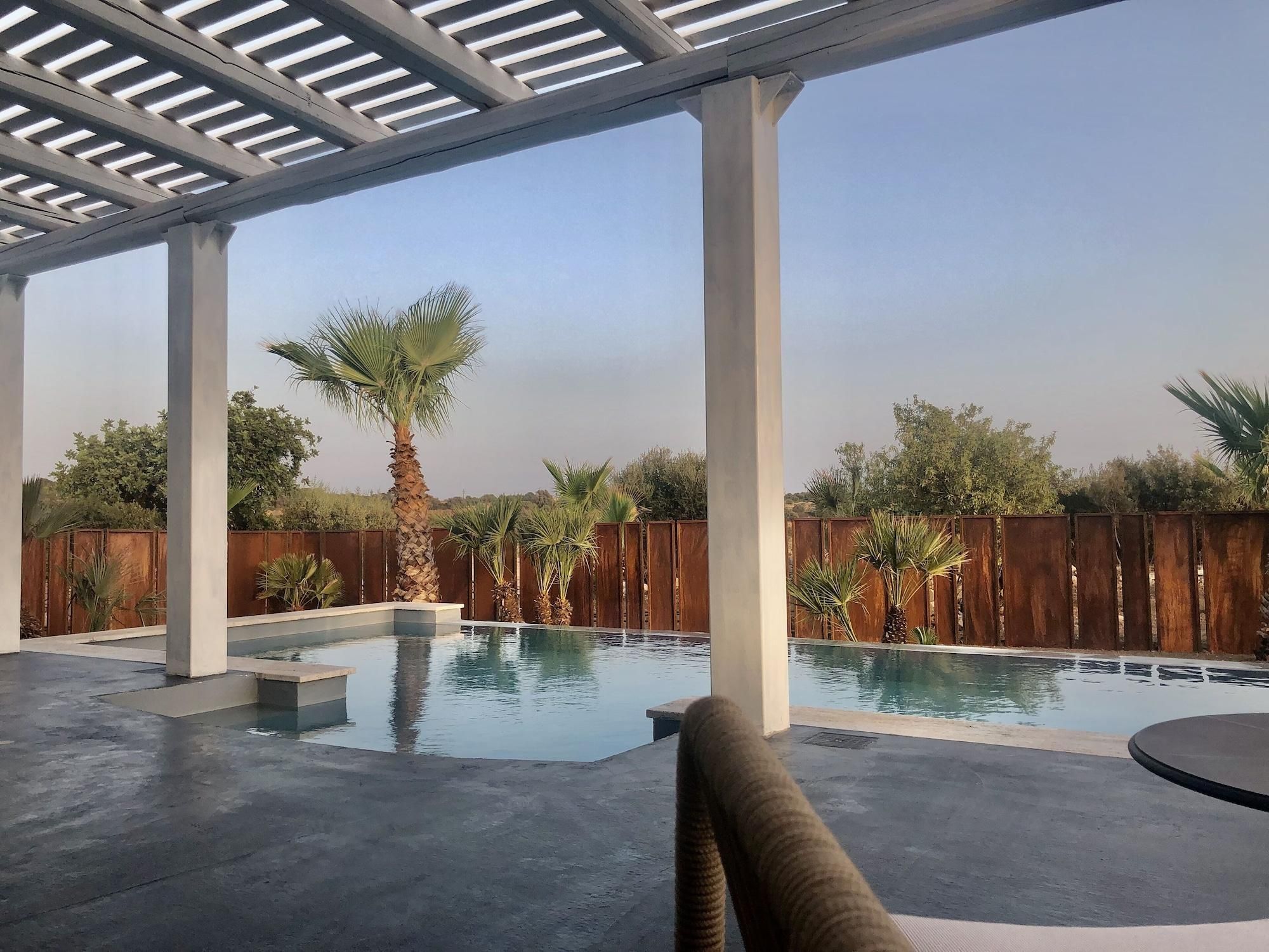 A covered outdoor swimming pool with concrete flooring and wooden pillars.