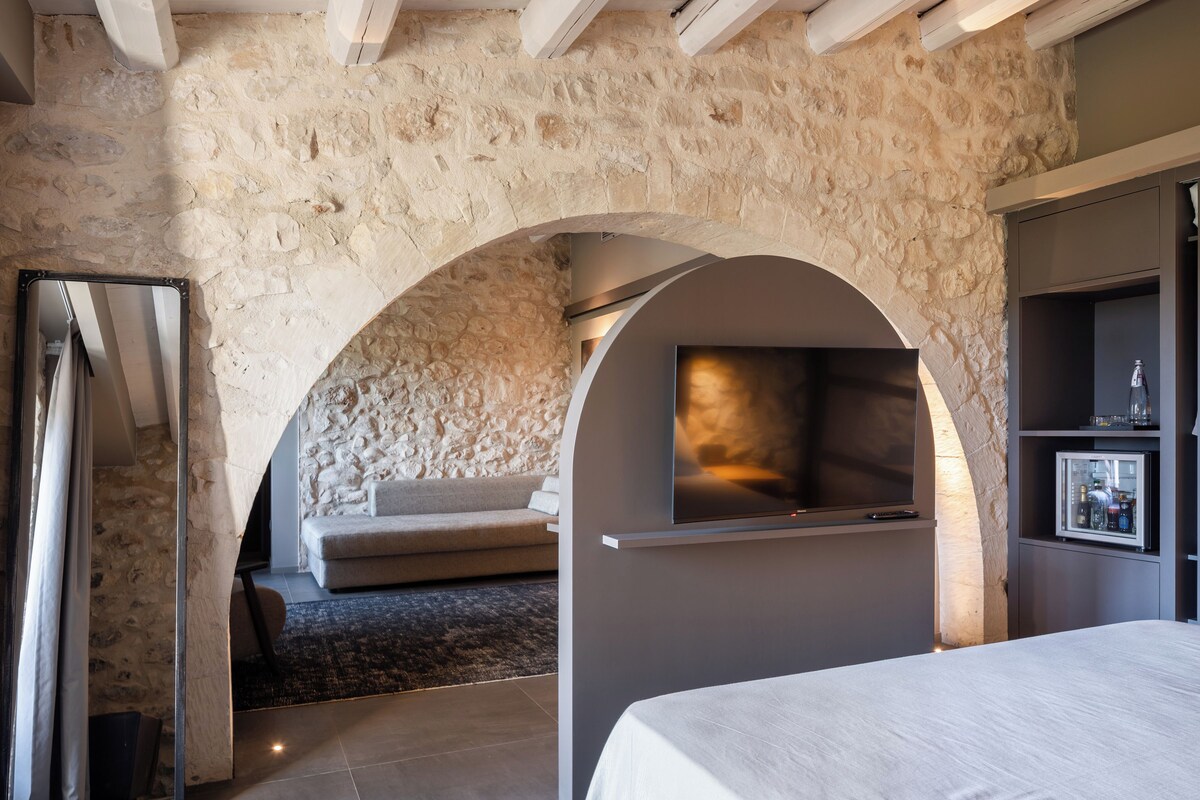 Ein modernes Zimmer mit einer Steinwand, einem Kamin, einer Couch und einem Bett.