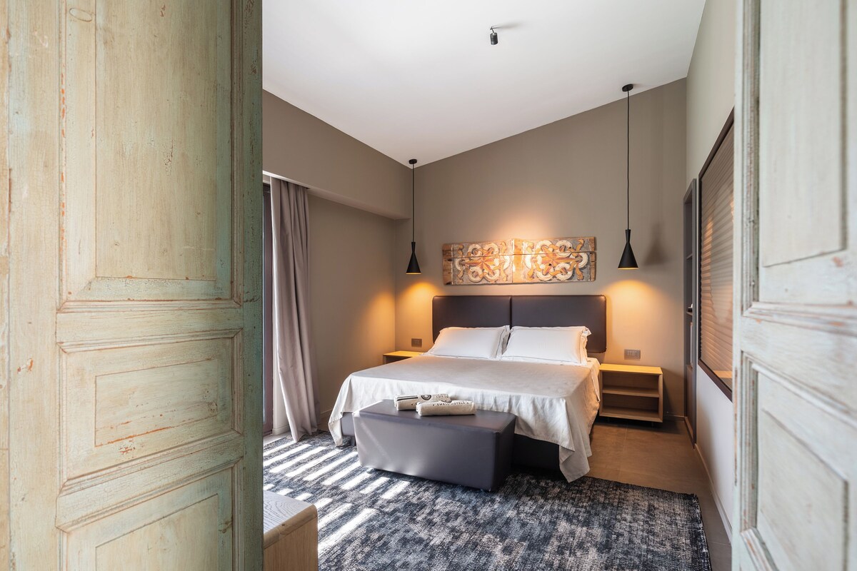 Ein Schlafzimmer mit einem Bett, Nachttischen, einer Bank und einem Wanddekor.