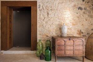Ein Zimmer mit einer Steinswand, einer Holztür mit der Aufschrift "SPA AREA" und einer hölzernen Kommode.